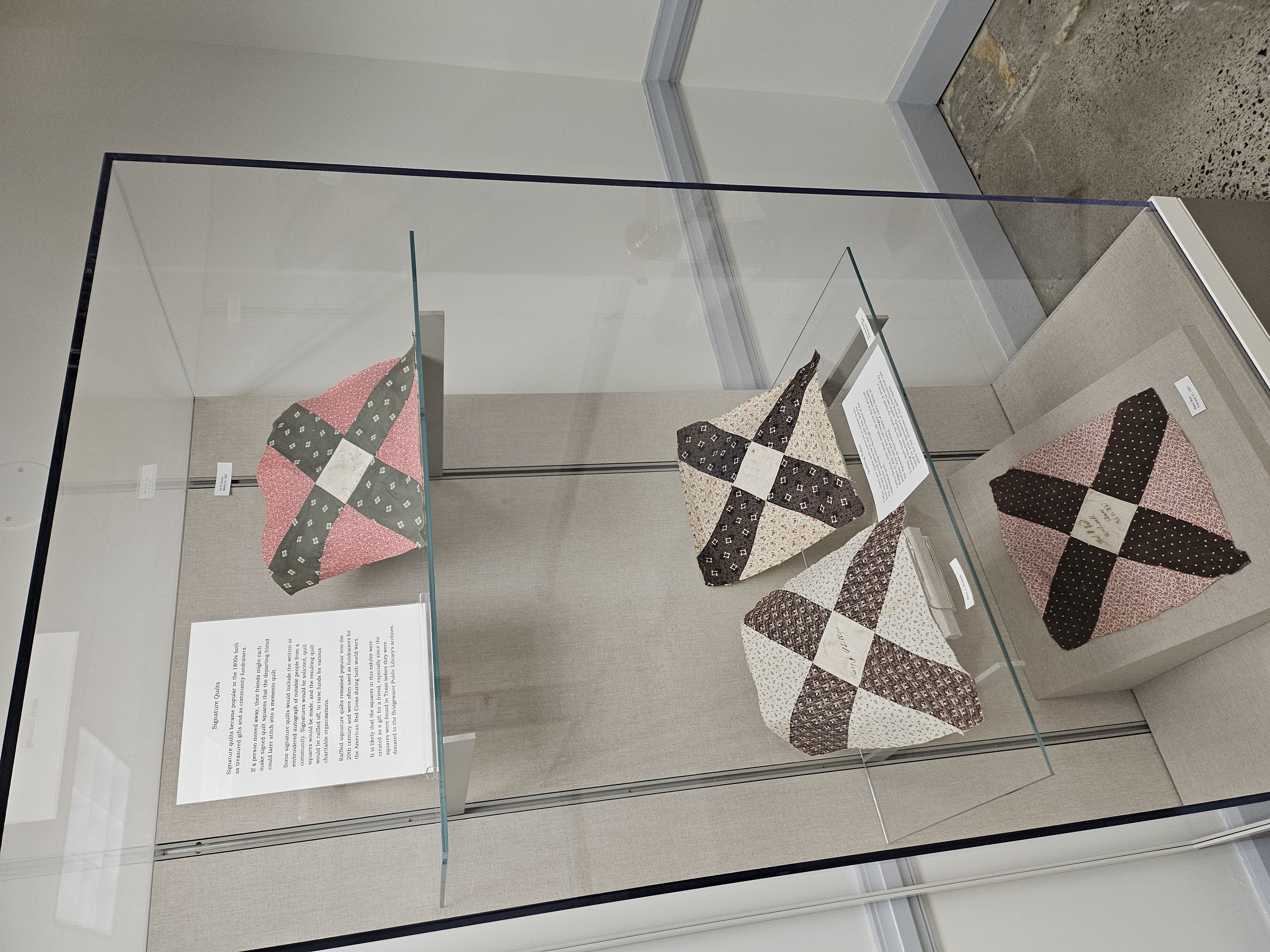 Quilt squares on display in a museum case